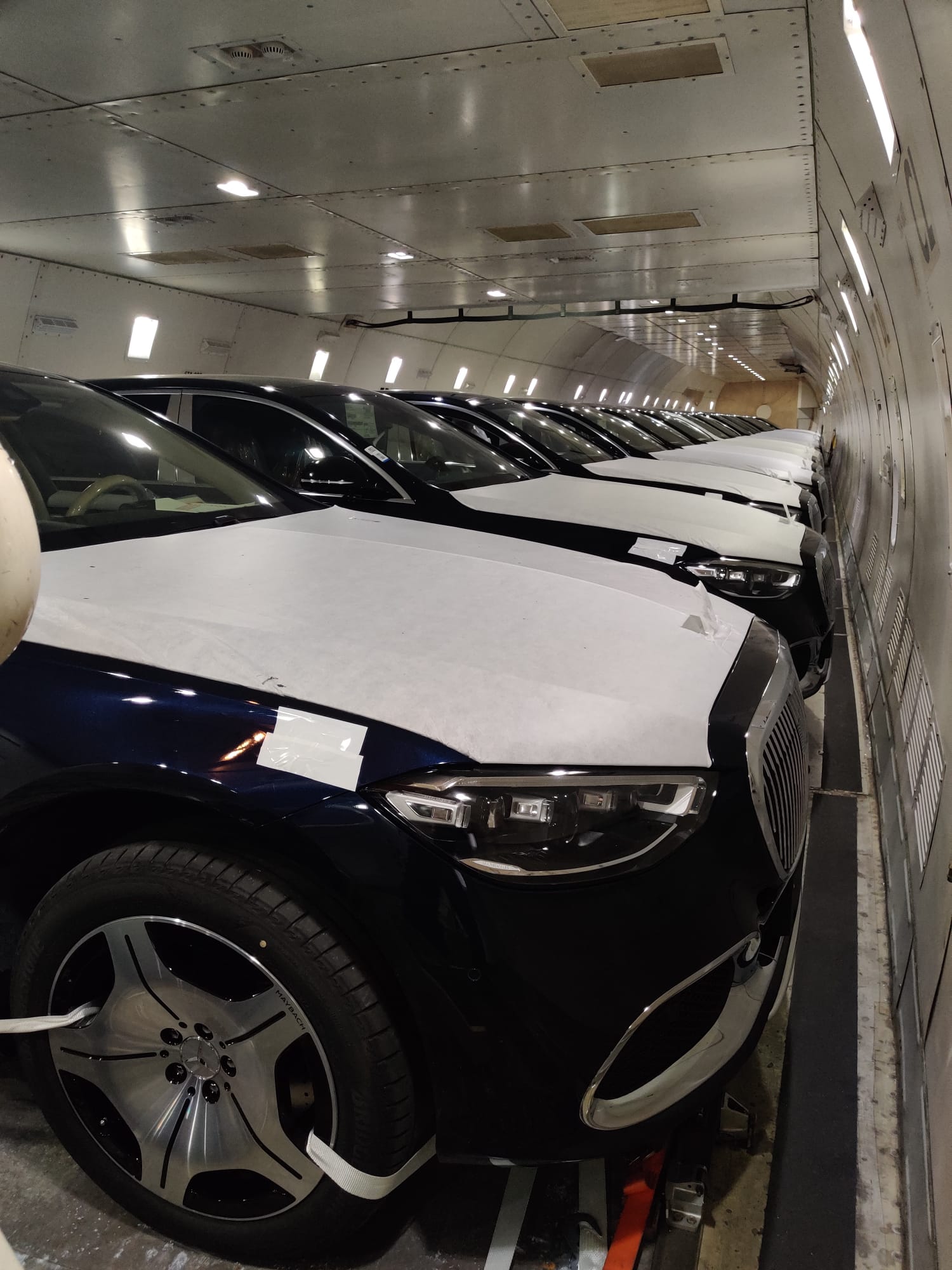 Row of luxury sedans with protective covers loaded inside a freighter